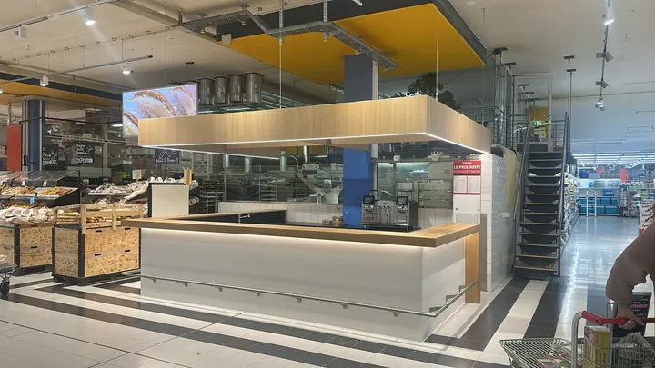 Bar pour l'espace clients pro d'Aligro Genève : comptoir en chêne et plafond suspendu, vue d'ensemble